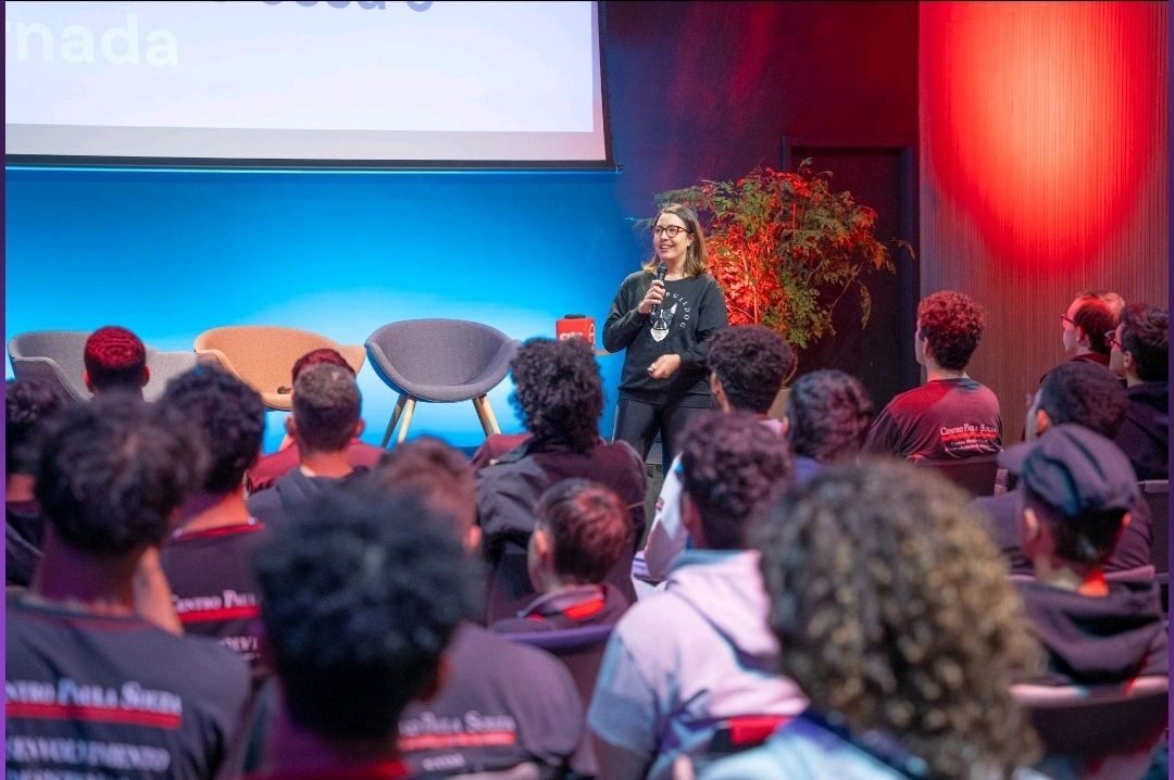 Oradora em palco perante a plateia num evento de tecnologia